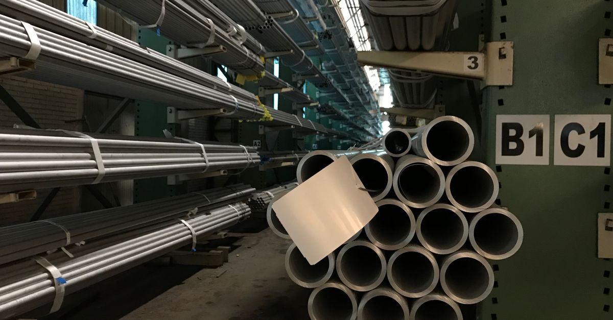 Tubos de acero industrial apilados en un almacén con estructura metálica